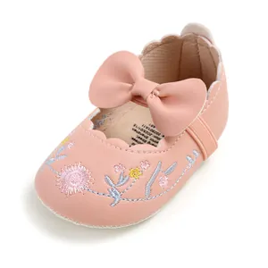 Detail view of pink baby princess shoe featuring floral embroidery and a leather bow.