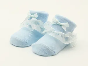 Nahaufnahme hellblauer Babysocken mit zarten Spitzenrüschen und einer Satinschleife