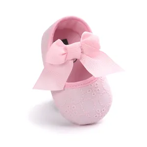 Detailed macro view of a pink embroidered baby princess shoe with a large decorative ribbon bow.