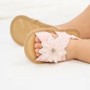 Vue détaillée de sandales roses pour bébé avec fleurs, perles et semelles souples