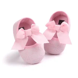 Detailed macro view of pink embroidered baby princess shoes with large soft ribbon bows