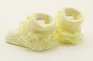Detailansicht gelber Babysocken mit gepunkteten Spitzenrüschen für besondere Anlässe