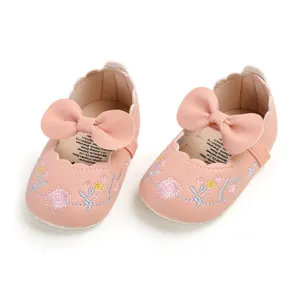 Close-up of pink baby princess shoes with delicate floral embroidery and a bow.