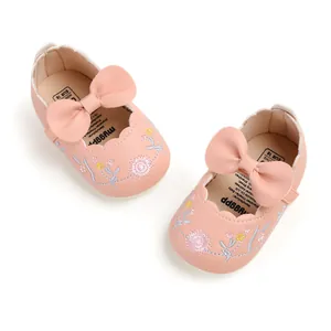 Detail view of pink embroidered baby princess shoes with a large decorative bow