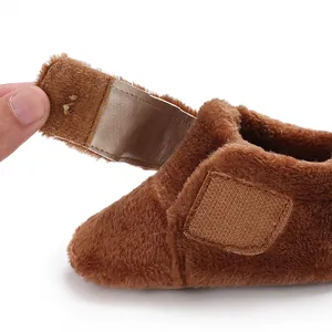 Close-up detail of the adjustable hook-and-loop strap on brown plush baby winter shoes