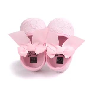 Close-up of pink embroidered baby princess shoes with large ribbon bows and soft soles