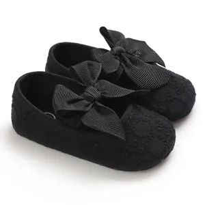 Détail rapproché des chaussures de princesse en dentelle noire pour bébé avec de gros nœuds