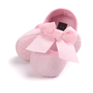 Detailed macro view of pink embroidered baby princess shoes with a large ribbon bow.