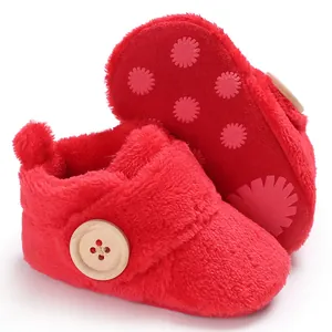 Detail view of red ultra-soft fuzzy baby booties with wooden button and anti-slip flower sole