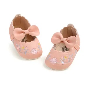Detailed view of pink embroidered baby princess shoes with leather bow accent