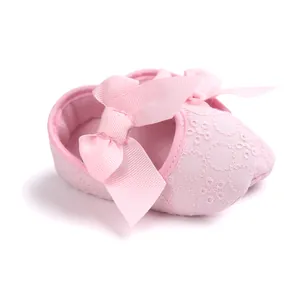 Macro detail of soft pink baby princess shoe featuring floral embroidery and a large ribbon bow