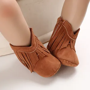 Close-up of brown suede baby boots with stylish tassel decoration and side zipper