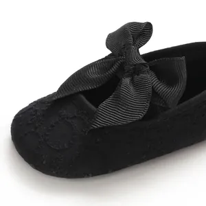 Gros plan de chaussures de princesse bébé noires avec dentelle délicate et nœud en ruban.