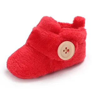 Close-up of a soft red plush baby shoe with a decorative wooden button detail