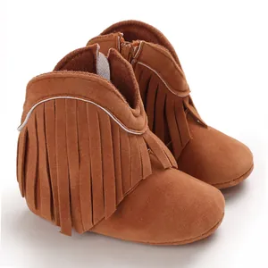 Close-up of brown suede infant boots with stylish fringe tassels for baby girls.