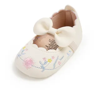 Close-up detailed view of cream embroidered baby princess shoes with a stylish bow accent