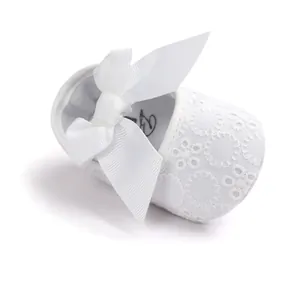 Detailed view of white embroidered cotton baby princess shoe featuring a large satin ribbon bow