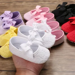 Gros plan de chaussures de princesse bébé blanches avec broderie et gros nœud