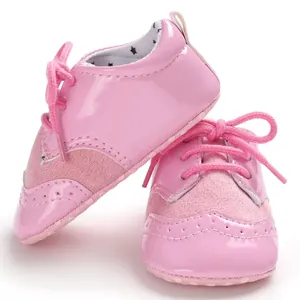 Detailed macro view of pink baby oxford walker shoes with wingtip embroidery and laces.