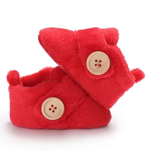 Detailed view of soft bright red plush baby walking shoes featuring large wooden buttons