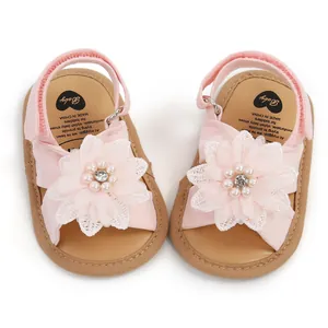 Détail de sandales roses pour bébé avec une grande fleur décorative en tissu et perles