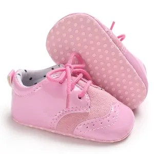 Close-up of pink baby pre-walker shoes with brogue details and dotted anti-slip sole