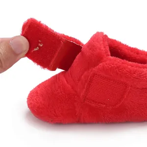 Close-up of red plush baby walking shoe featuring adjustable Velcro strap closure.