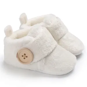 Close-up of white fuzzy baby booties with a large decorative wooden button detail