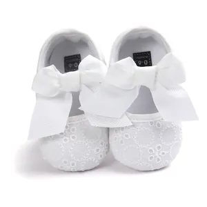 Detailed view of white embroidered baby princess shoes with a large soft white bow