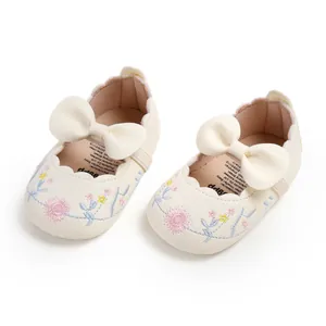 Detailed view of embroidered cream baby princess shoes with a soft leather bow.
