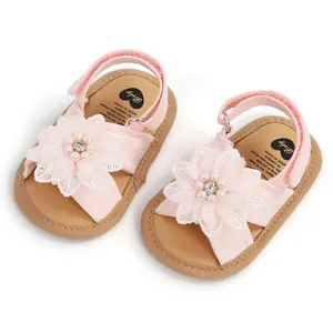 Vue détaillée de sandales roses pour bébé avec grandes fleurs en tissu et perles