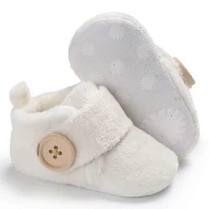 Soft white fuzzy baby walking shoes with wooden button detail and non-slip sole.
