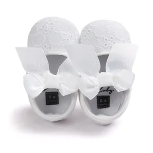 Detail view of white embroidered baby princess shoes with soft soles and large bows