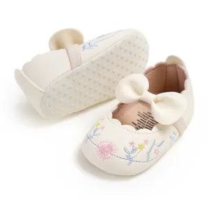 Detailed view of elegant cream baby shoes with floral embroidery and bow decoration