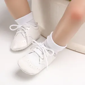 Close-up detail of white baby brogue pre-walker shoes featuring soft soles and lace-up design