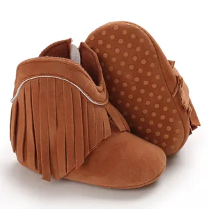 Macro detail of brown suede baby boots featuring stylish fringe tassels and anti-slip sole.