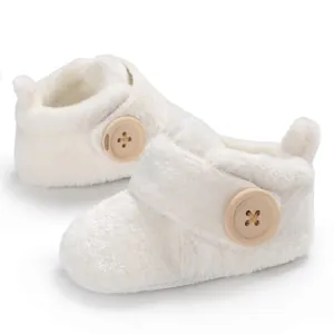 Close-up detail of white fuzzy baby walking shoes featuring a decorative wooden button