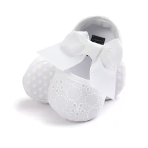 Macro view of white embroidered baby princess shoes featuring a large grosgrain bow