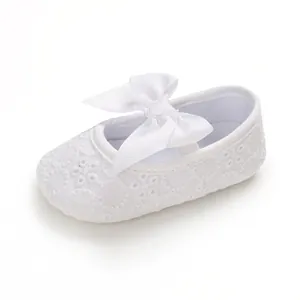 Gros plan d'une chaussure de princesse blanche pour bébé avec dentelle et grand nœud.