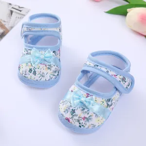 Detailed view of floral print baby walking shoes featuring a light blue satin bow and soft sole