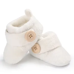 Detailed view of soft white plush baby walking booties with decorative wooden buttons