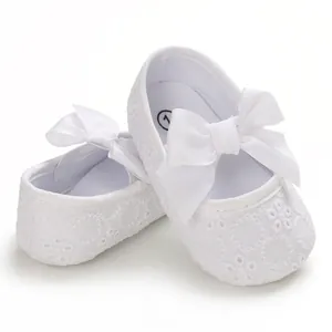 Vue détaillée de chaussures de princesse blanches pour bébé avec dentelle et nœud