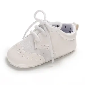 Detailed view of white infant pre-walker leather shoes with brogue pattern and soft laces