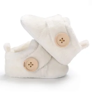High-quality detailed shot of white plush baby booties with large wooden buttons