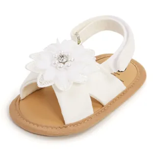 Détail de sandales blanches pour bébé avec grande fleur en tissu et perles