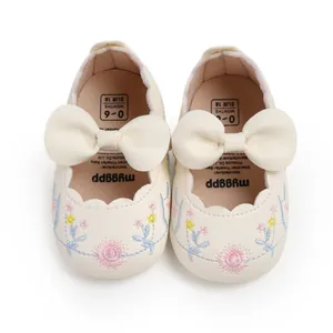 Overhead detail of cream baby princess shoes with floral embroidery and large bows