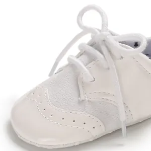Detailed macro view of white infant leather walking shoes with brogue wingtip design