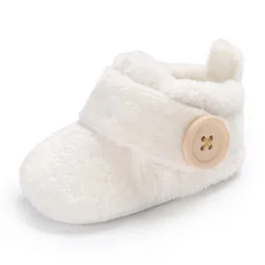 Detail view of a soft white plush baby shoe with a large wooden button closure.