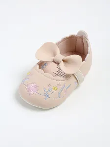 Close-up detail of embroidered baby princess shoes with a large decorative bow