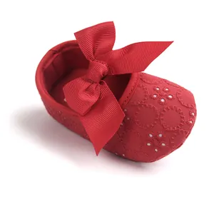 Detailed macro view of the red baby princess shoe with embroidery and elegant ribbon bow.